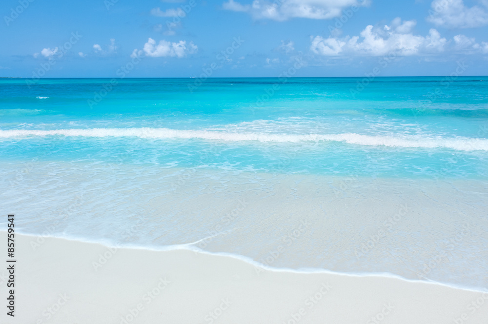 Turquoise waters and gentle waves on a white sand Caribbean beach.