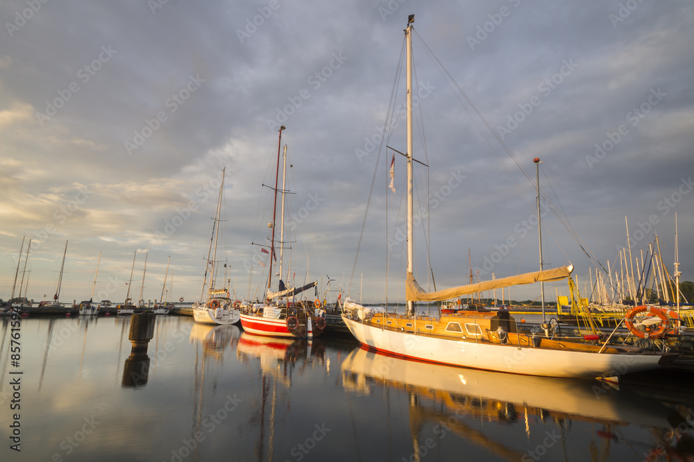 Sailing boats in marina at sunset.