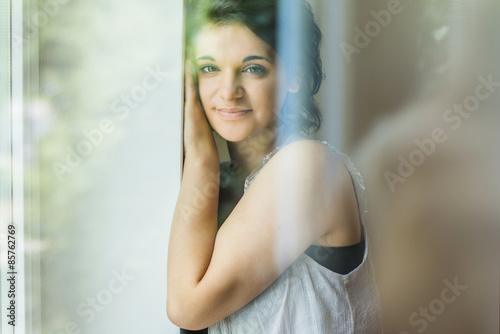 Portrait of young woman, through window glass with reflections