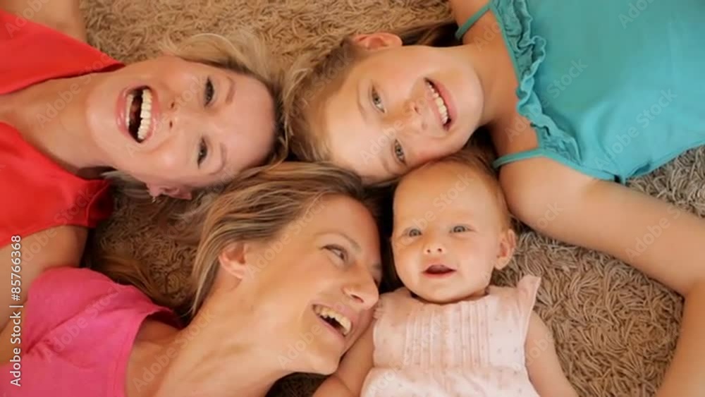 Overhead shot of four generations of females lying on rug together. Overhead shot of four generations of females lying on rug together.