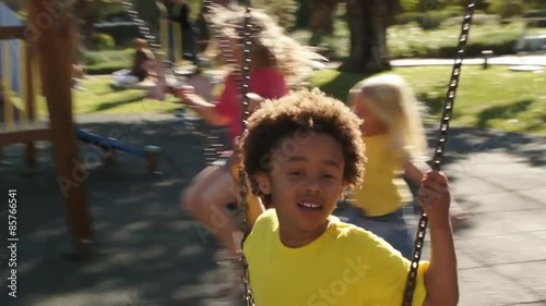 Slow motion of four children playing on swings in park. photo