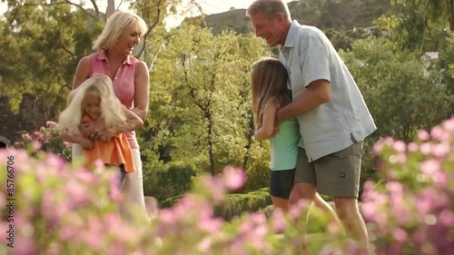 Slow motion of grandparents and grandchildren twirling around in park.