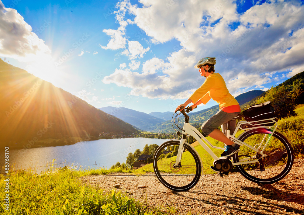 Naklejka premium woman with e-bike above a lake in sunset/e-power 11