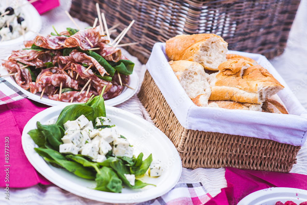 Lite appetizer of salami, basil, cheese and bread/Bread, salami, basil and cheese on the tablecloth during a picnic in the park. Lite appetizer of salami, basil, cheese and bread/Bread, salami, basil and cheese on the tablecloth during a picnic in the park.
