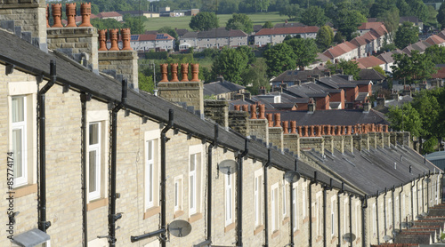 Red chimney tops atop row of stone built terraced houses in Lancashire England photo
