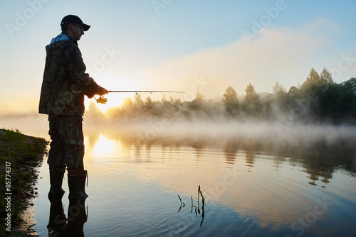 Fototapeta fisher fishing on foggy sunrise