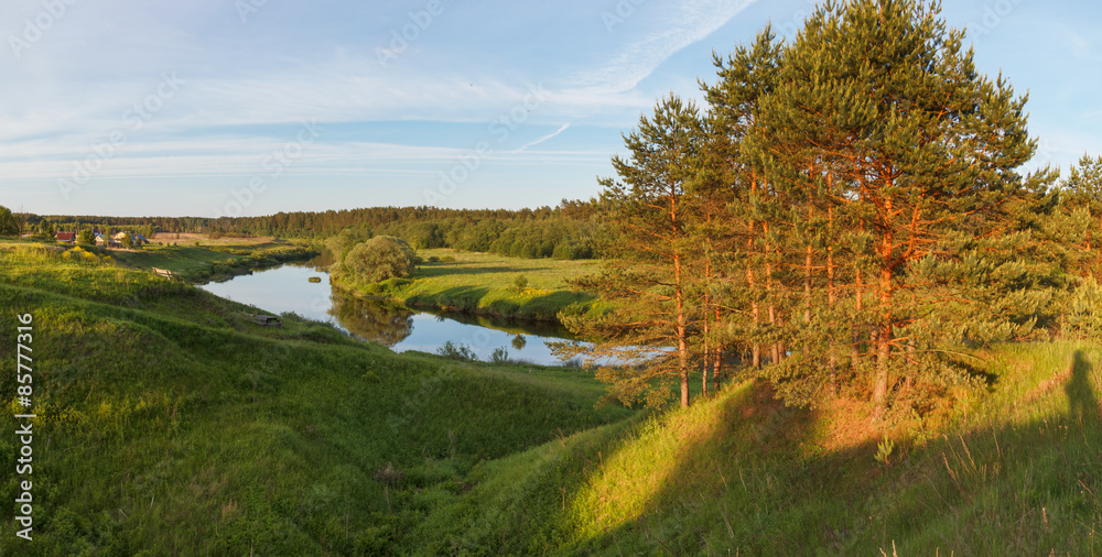Summer panoramic landscape with the river on in the evening sun