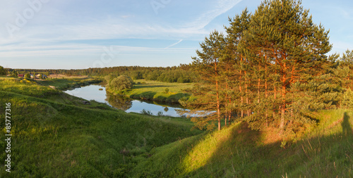 Summer panoramic landscape with the river on in the evening sun