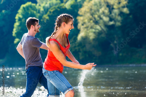 Mann und Frau flippen Steine am Fluss photo