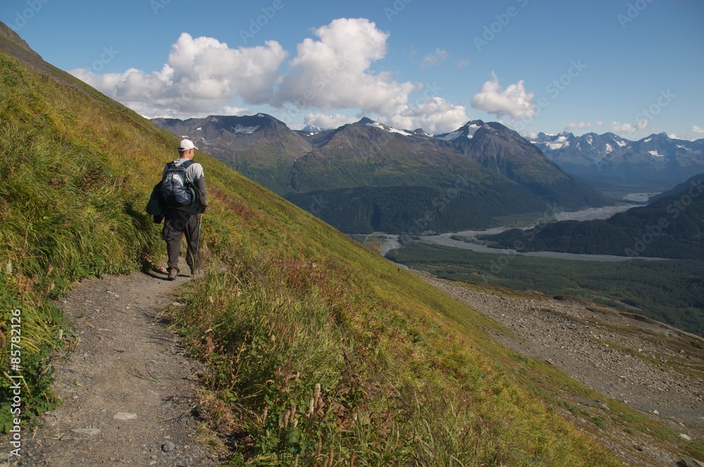 hiking on a mountain in alaska with cloudy skies in the background and views over a valley