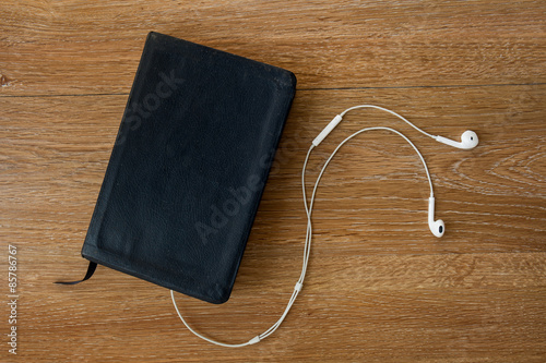 Contemporary image of a Bible with headphones. Hearing the voice