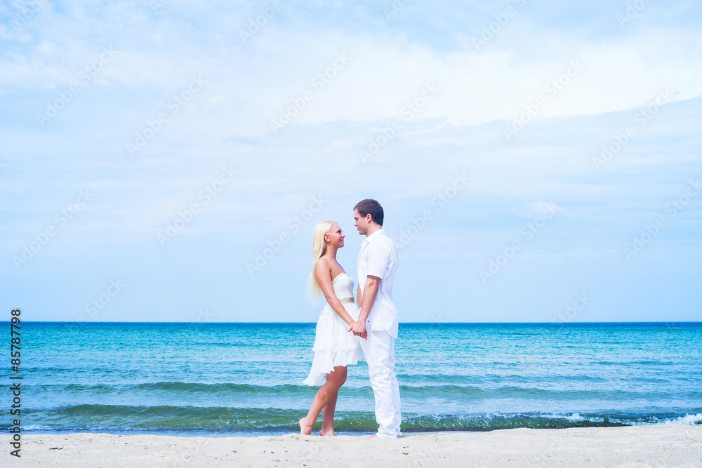 Loving couple walking and embracing on a tropical summer beach Loving couple walking and embracing on a tropical summer beach