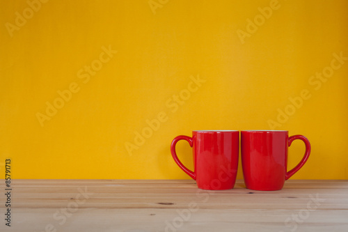 Two cups of coffee and stand together to be heart shape on yello