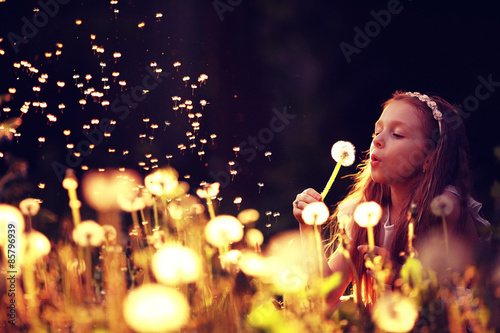 Fotografie girl blowing a dandelion seeds flying