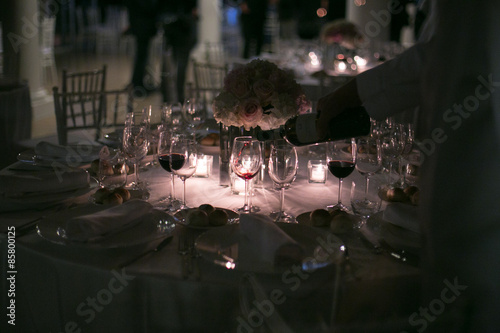 Cameriere che versa il vino in un calice a lume di candela photo