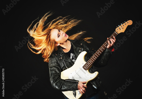 young woman with waving hair play electric guitar isolated on bl