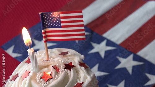 Close up of birthday cupcake with American flag decorations on it and background.  Red white and blue.