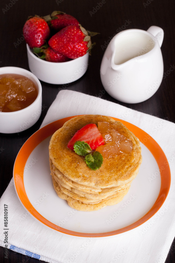 Delicious pancakes with fresh strawberries on a plate, jam and m Delicious pancakes with fresh strawberries on a plate, jam and m