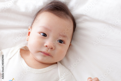 asian baby lay down on bed