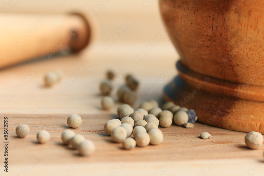 white pepper seeds on wooden background.