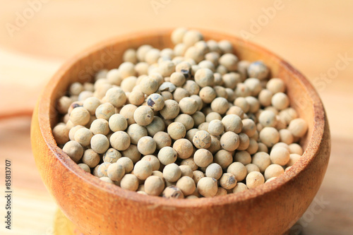 white pepper seeds on wooden background.