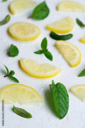 Fresh lemon slices with mint leaves on white background