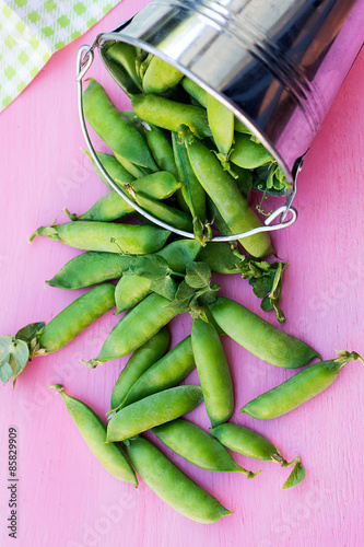 Pods of green peas in a bucket