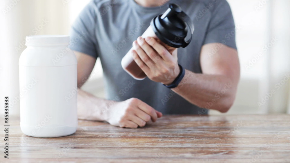 close up of man with protein shake bottle and jar close up of man with protein shake bottle and jar