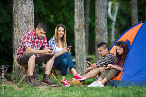Four teenagers camping in nature, spanding time with thier mobile phones © bokan