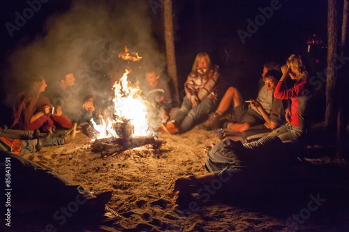 Tourists around the campfire at night.