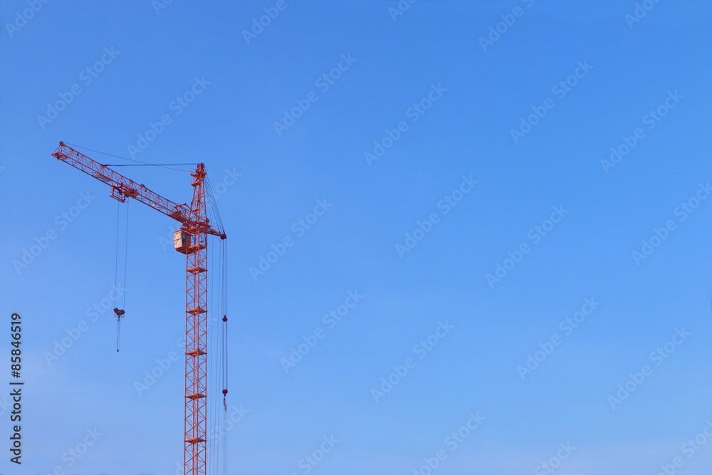 Large orange crane without cargo on blue clear sky background