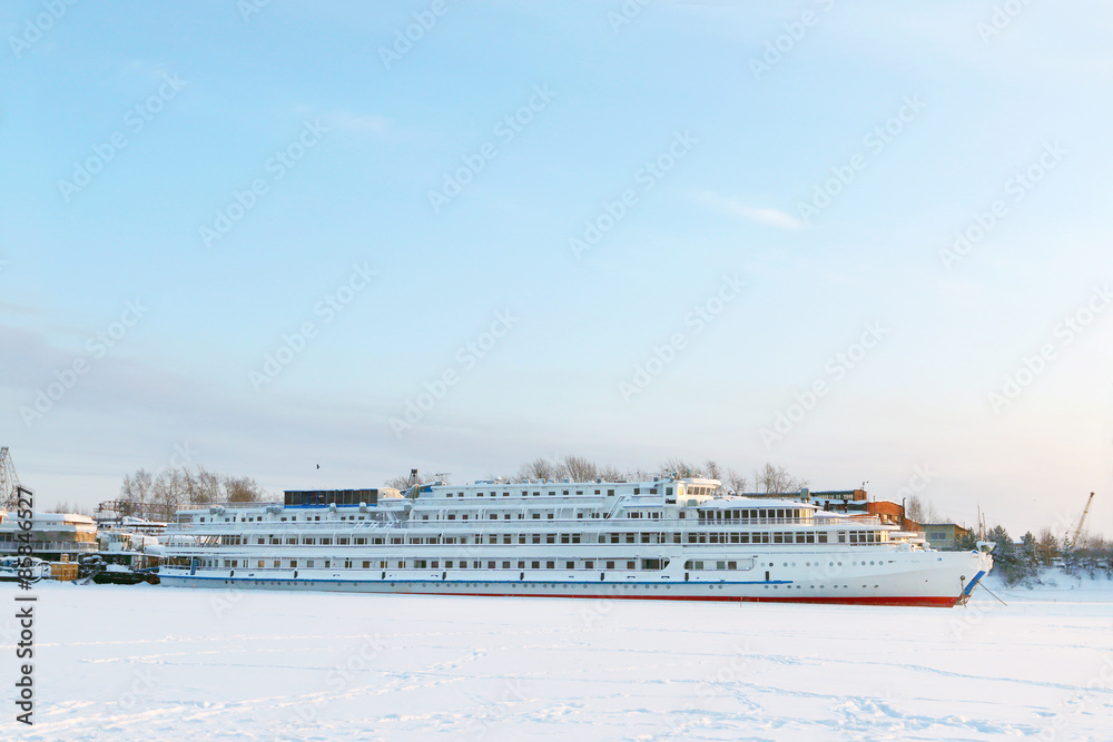 Large white beautiful passenger ship in frozen river in winter 