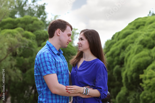 Man and woman look at each other and hold hands in park