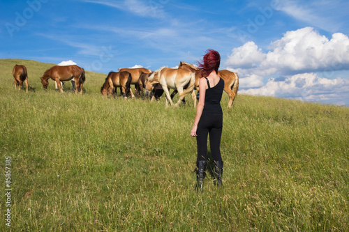 Giovane donna vicino a dei cavalli selvaggi