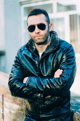 Sexy guy with attitude wearing leather jacket and sunglasses out
