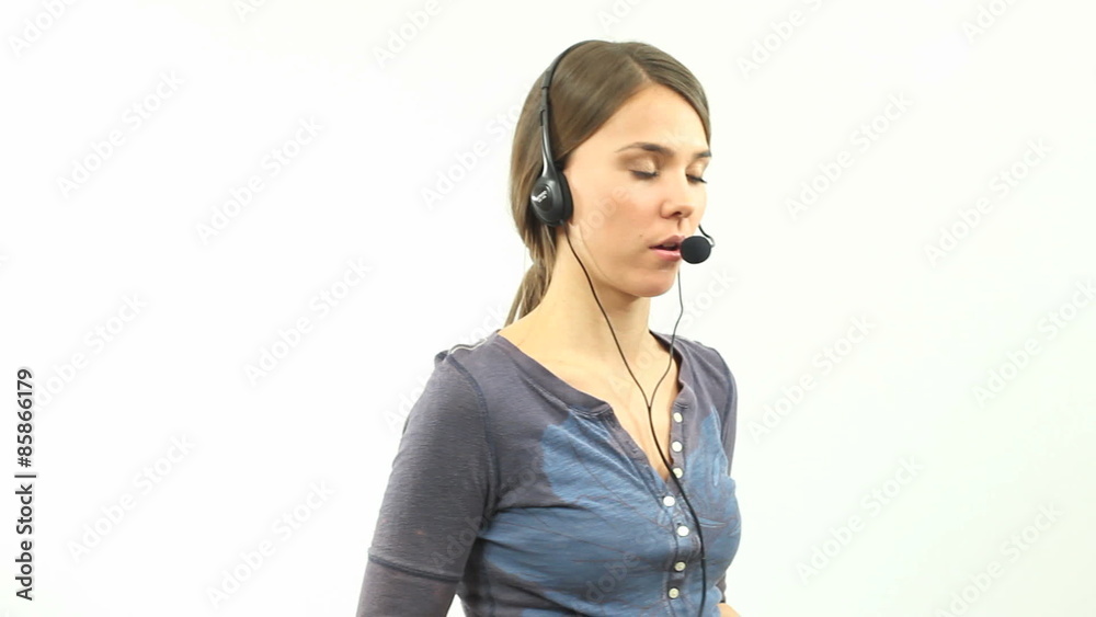 Helpdesk Operator on the Job - Young woman wearing a headset talks to someone calling in to the helpdesk to get support and advice. Helpdesk Operator on the Job - Young woman wearing a headset talks to someone calling in to the helpdesk to get support and advice.
