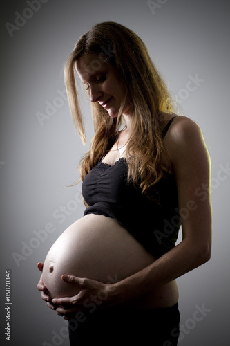 Mujer embarazada en clave baja con luz de contra amarilla photo