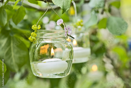 Kerze im Glass hängt im Baum