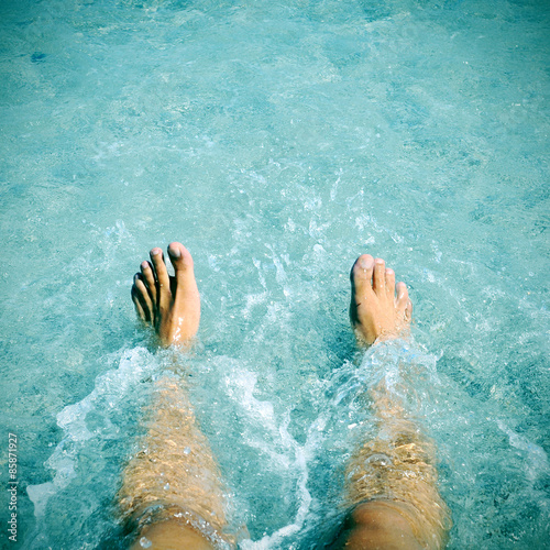 young man with his legs into the water, slight vignette added photo