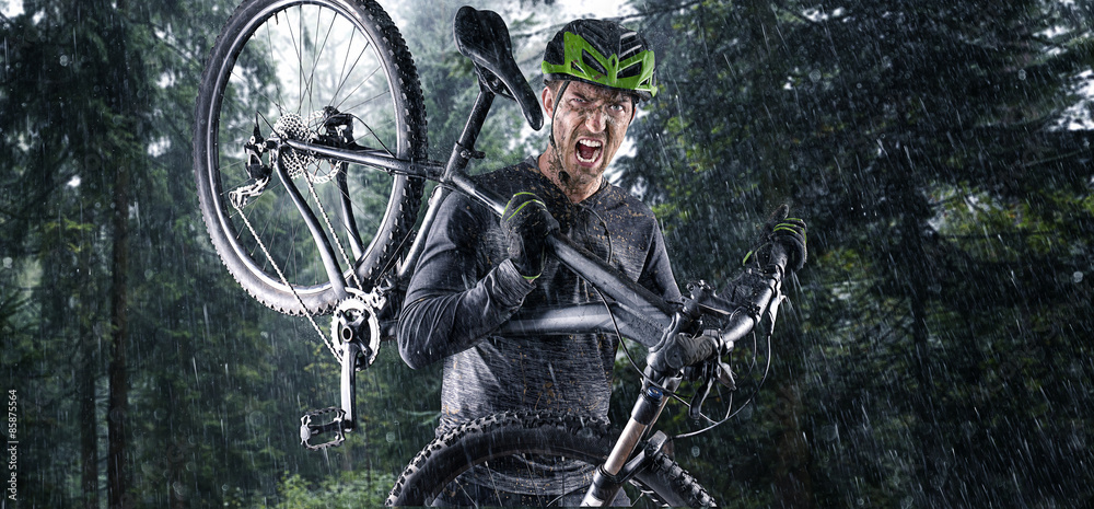 Obraz premium Nasser Mountainbiker mit Fahrrad auf der schulter