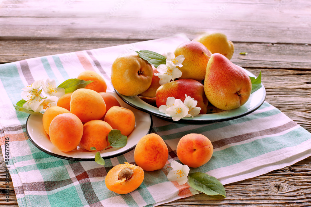 Apricots and peaches on plates with syringa flowers 