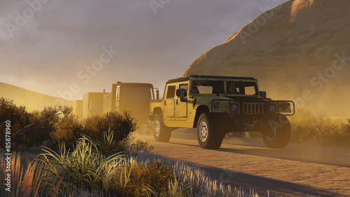 Military motorcade with SUV ahead on a dirt road at evening time