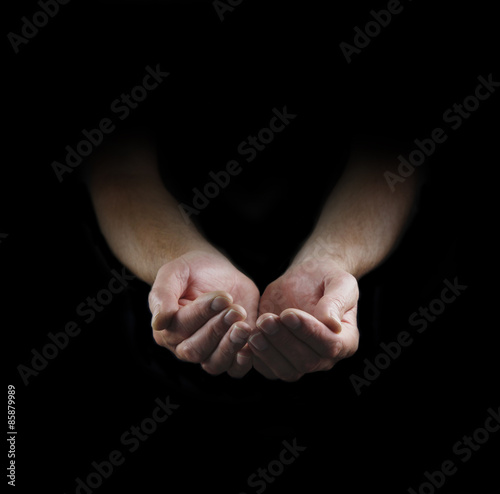 Please Help - Man's cupped hands emerging from darkness with plenty of copy space around