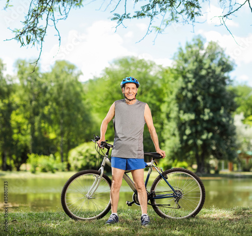 Senior cyclist posing by a pond in a park