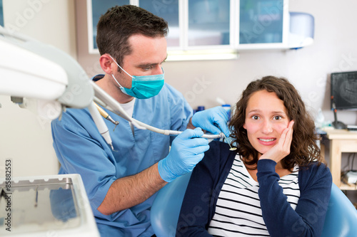 Young attractive woman scared to being cured by a dentist