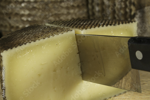 Close-up of cheese knife cutting a sheep milk cheese