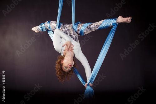 Young gymnast doing exercise on aerial silks