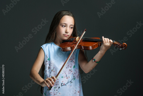 The young girl playing the violin on the dark background