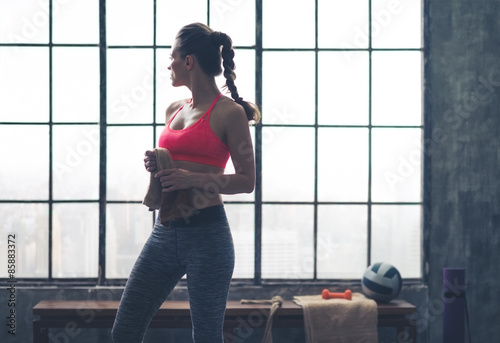 Woman looking over shoulder holding towel in city loft gym