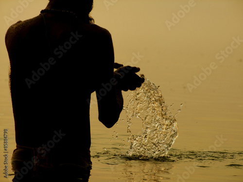 Bénarès. Recueillement au bord du Gange,barque sur l'eau sacrée du Gange. Soleil levant. photo